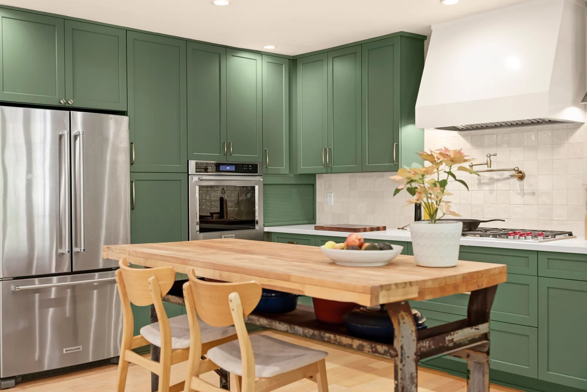 Remodeled green kitchen with wood dining table